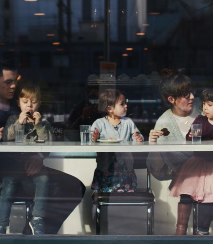 Family with young children eating at a restaurant counter.