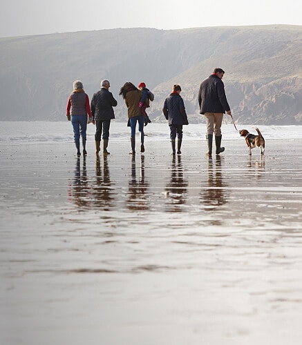 Group of people walking along the beach in the winter.