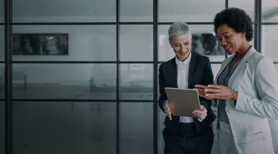 Women review tablet in glass office