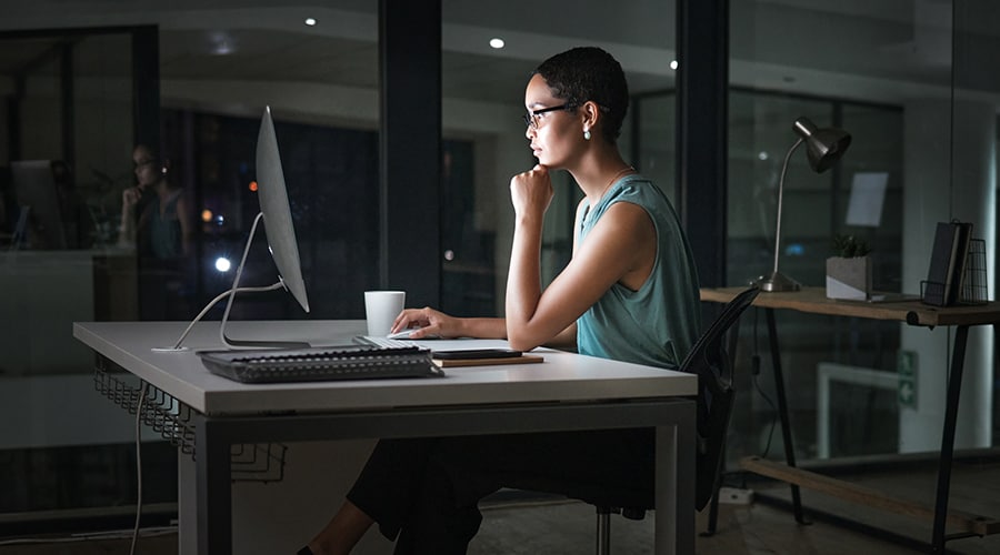 Woman sitting at her desk after dark.