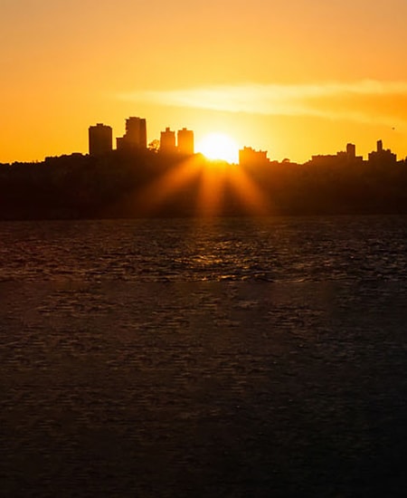 Sun shining behind city skyline.