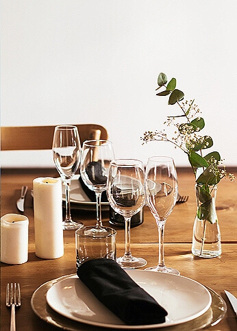 Various dishware and elegant decorations placed on wooden banquet table.