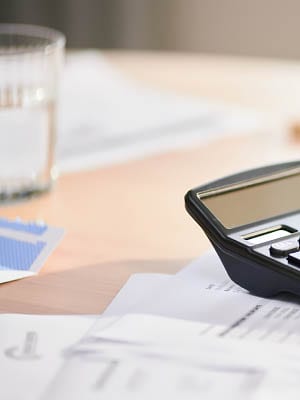 Calculator and glass of water with paperwork.