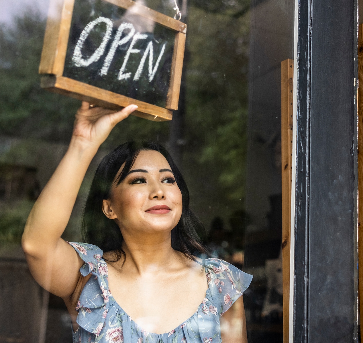 Woman placing an "open" sign in a doorway.