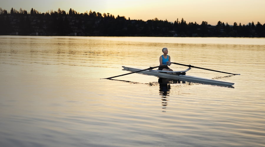 Older woman in a kayak in the middle of a lake.