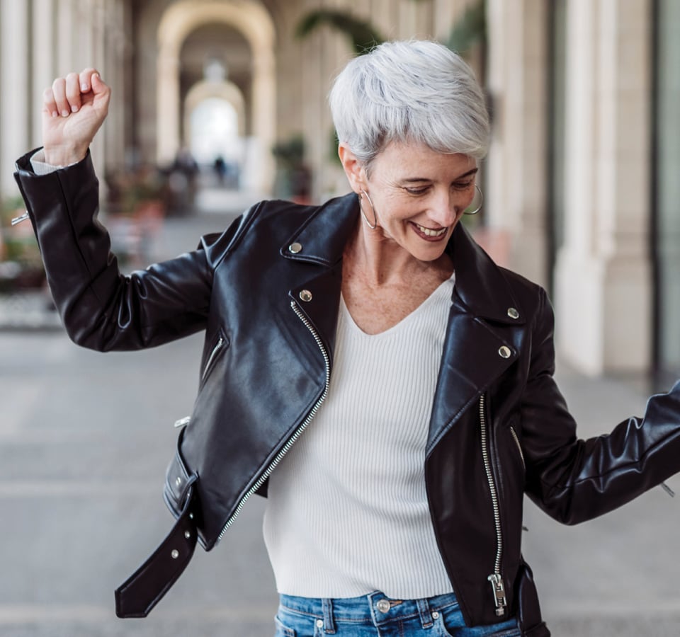 Woman with grey hair and leather jacket dancing.