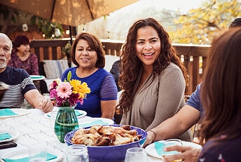 Multigenerational family enjoying a meal around a table on their deck.