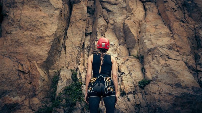 Rock climber facing a cliff wall