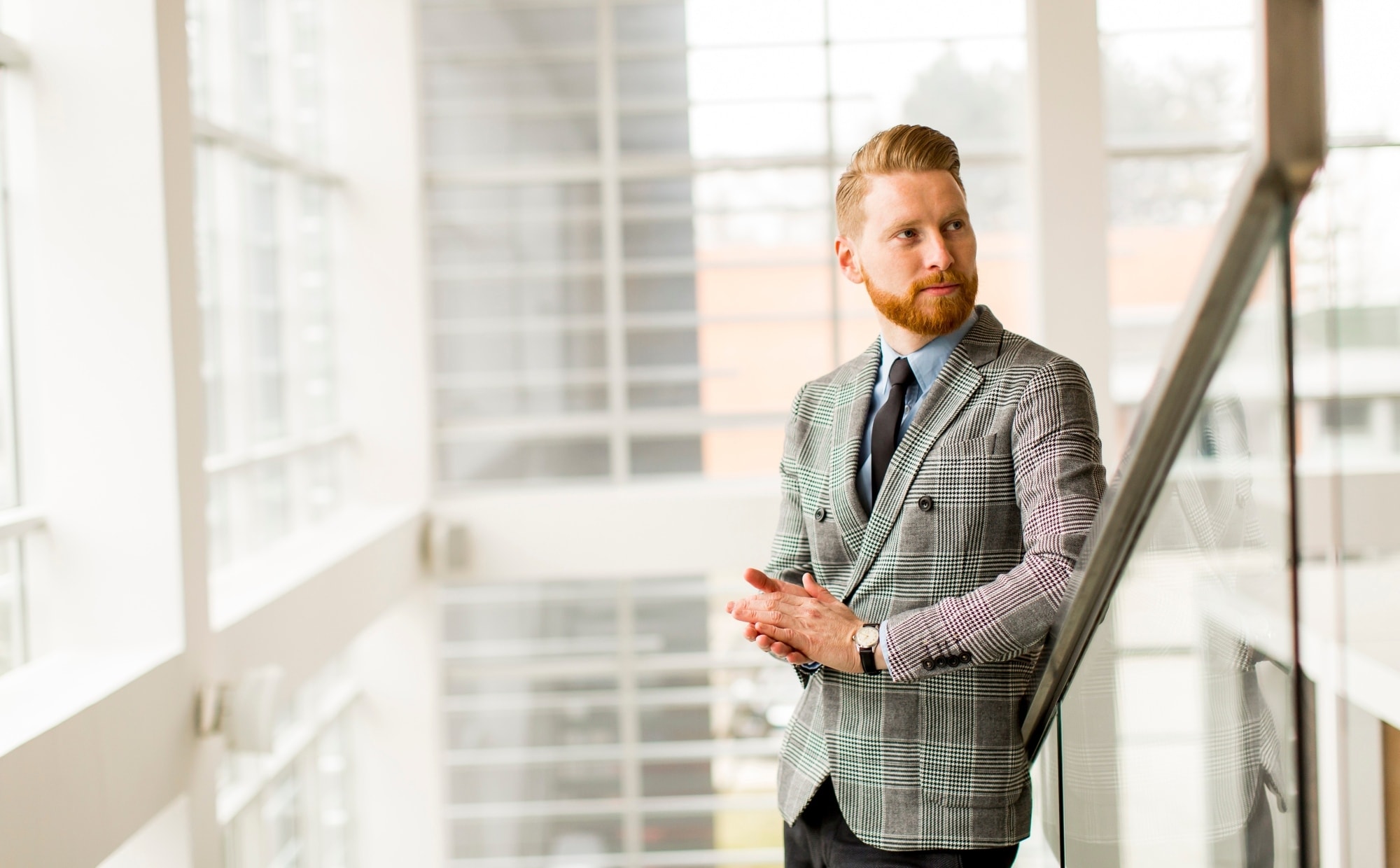 man stands in stairwell in glass building