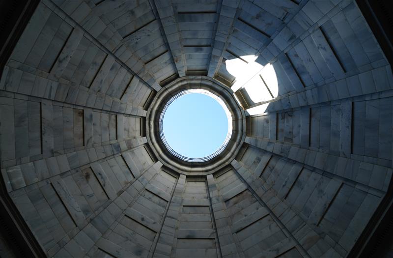 inside building looking up column to blue sky above