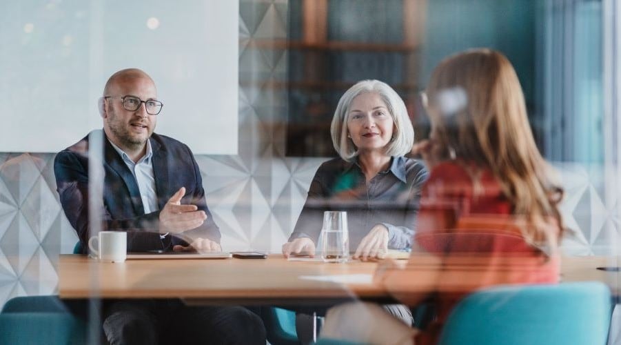 three people around wooden table in meeting